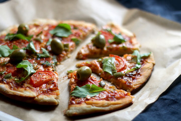 Homemade vegetarian pizza with tomato sauce, two types of cheese, tomatoes, peppers, arugula, olives and herbs. Selective focus.