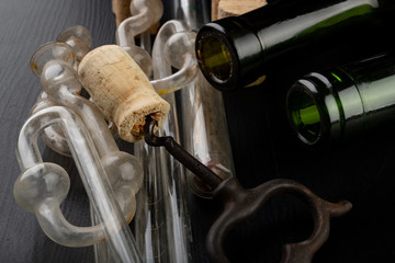 Fermentation tube and corkscrew on a black table. Accessories needed to prepare homemade wine.