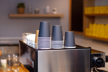 disposable coffee cups on a coffee machine in a dark interior with lamps