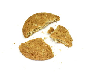 Broken biscuit with falling crumbs down. Round whole wheat biscuit, cookie with raisins isolated on white background. Biscuits with whole-wheat (wholemeal) flour isolated on white.