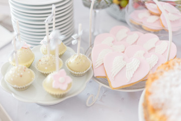 Sweet table at Christening or First Communion party. Heart shaped cookies with angel wings.