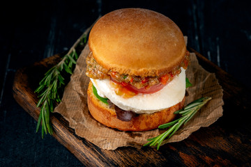 Vegetable homemade Burger made from fried eggplant, tomato, lettuce avocado and mozzarella cheese on a wooden Board.