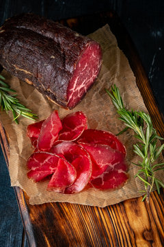 Cut into pieces smoked bresaola on a cutting Board. Italian antipasti prosciutto