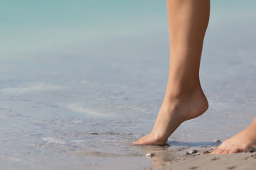 Young girl barefoot stands in the sand and wants to enter the water.