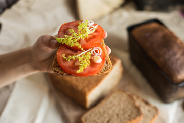 homemade sandwich with fresh sourdough wheat bread and tomato and some greens on the rustic background