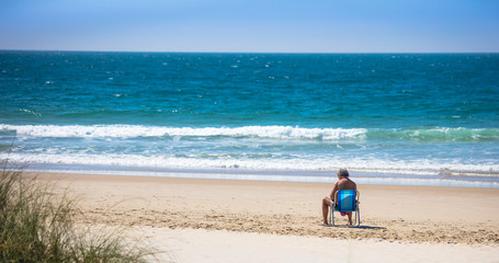 Fototapeta na wymiar Pessoa sentada na cadeira em uma praia