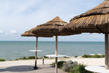 table straw umbrellas on the beach empty in summer