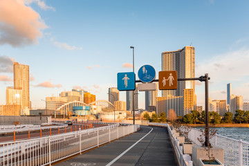 Road signs on a path for pedestrian and cyclists on Tokyo waterfront at sunset