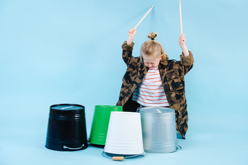Little boy using drumsticks on iron and plastic buckets. Playing rhythm.