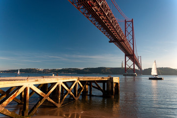 Scenic view of the 25 of April Bridge (Ponte 25 de Abril) over the Tagus River with sailing boats, in the city of Lisbon, Portugal