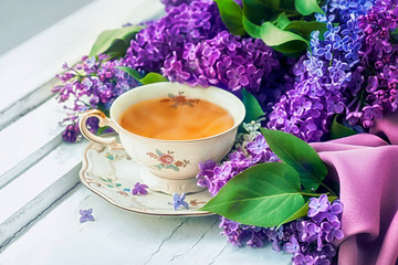 Lilac flowers and a сup of tea on a wooden windowsill.
