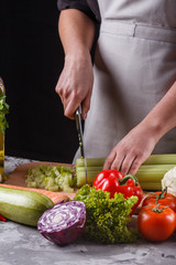 young woman in a gray apron cuts a celery