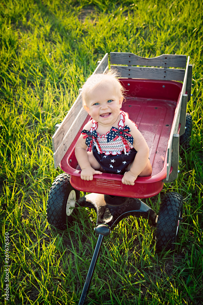 Wall mural Fourth of July baby girl in red wagon