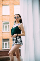 Fototapeta premium Sexy girl in sunglasses t-shirt and short shorts near the columns