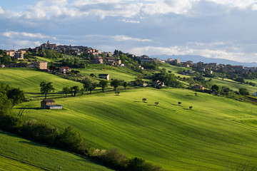 Fototapeta na wymiar Grassy hills and town in Italy