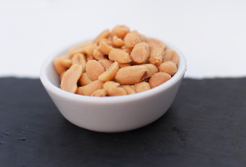 bowl of salted peanuts on black and white background, selective focus