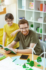 Obraz premium Smiling interested man in clear glasses carrying opened book