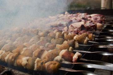 Preparation of shish kebab on skewers, close-up. BBQ grill with lamb meat and potatoes