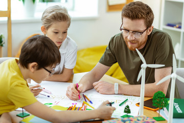 Ginger good-looking teacher with red beard writing down on the paper