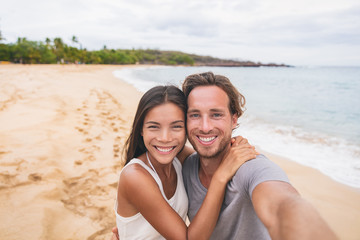 Two friends taking self portrait picture with phone. Smiling young interracial couple taking selfie...