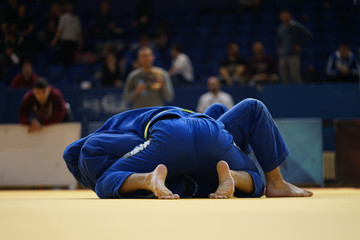 Brazilian Jiu-Jitsu BJJ judo tournament fight two fighters in blue gi kimono on the tatami in side...