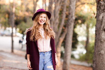Smiling teen girl 14-16 year old wearing stylish jacket and hat walking in park closeup. Teenagerhood.