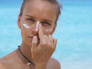 portrait of a beautiful girl surfer applying sunscreen on her face.