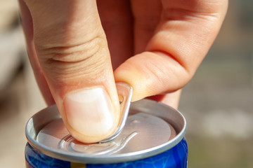 Man's hands opening can of beer close up at sunny day. Fresh drink at warm day. Alcohol drink.