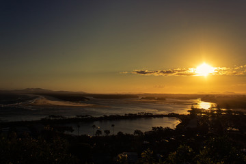 Flat sand dunes at delta of Nambucca river entering Pacific ocean through wide sandy beach of Australian coast around Nambucca heads town at sunset - aerial view