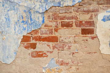 Fragment of an old brick wall with partially preserved blue plaster. Background. Texture.