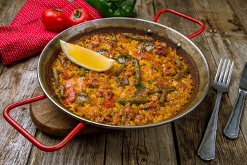 paella with chicken on wooden background
