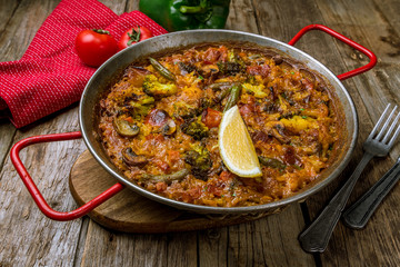 Spanish paella with vegetables on wooden background
