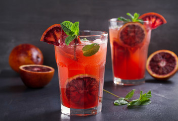 Two glasses of blood orange or red orange cocktail with slices of citrus fruits and mint - image
