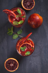 Two glasses of blood orange or red orange cocktail with slices of citrus fruits and mint - image
