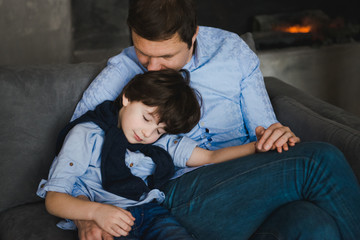 Father with little son sitting on the sofa. Father's day. Happy young father embracing kid sitting on sofa, loving caring dad hugging little boy. Father with little boy using digital tablet at home