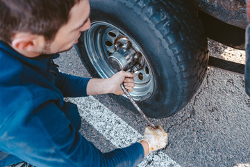 Man unscrews the bolts on the wheel