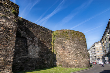 Fototapeta na wymiar Great medieval stone wall surrounding the city next to the road. Galician city of Lugo, Spain.