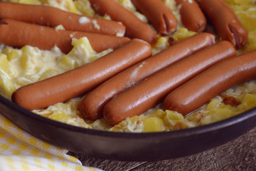 Sausages and fried potatoes in a large frying pan. Men's kitchen. Simple homemade food.