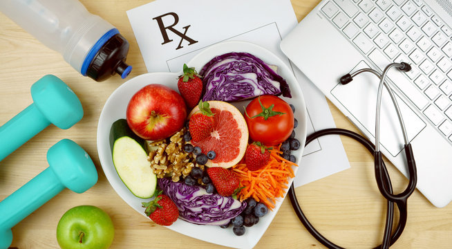 Prescription for good health overhead with stethoscope, healthy fresh food and exercise equipment.