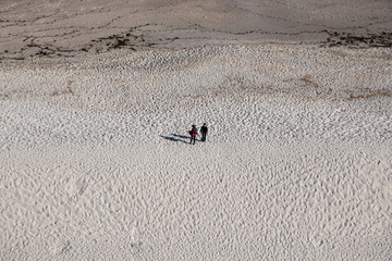 Aerial view of two women dressed in a large beach with white sand. Riazor beach in A Coruña, Galicia.