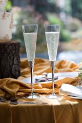 full champagne flutes at wedding with cake on rustic wood stand in background