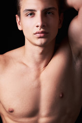 Studio portrait of handsome muscular shirtless young man isolated on black