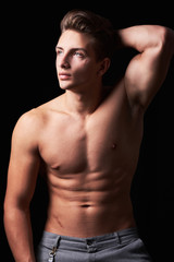 Fototapeta na wymiar Studio portrait of handsome muscular shirtless young man isolated on black