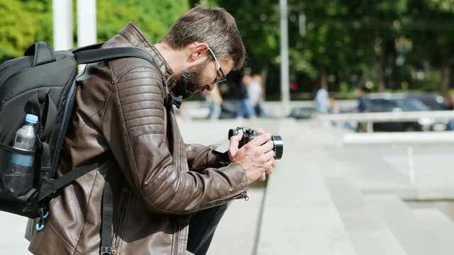 Bearded man with camera takes a video in the city street, blogger takes vlog