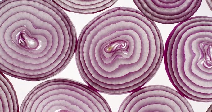 Slices of red onion rotating on a bright white background. Close up top view, shot on RED 6K camera