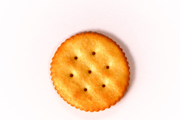 Top view of one round buttery cracker with holes and salt on white background.