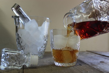 Crystal decanter pouring whiskey over ice