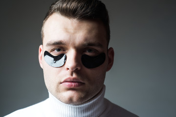 Beauty treatment. Skin care. Metrosexual concept. Focused treatments for under eye area. Minimizes puffiness and reduce dark circles. Eye patches for men. Man with black eye patches close up face
