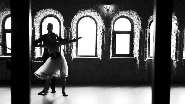 Beautiful ballet couple. Young professional sensual couple in beautiful costumes dancing together. Studio of ballet dance. Monochrome style.