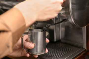 Fototapeta na wymiar Barista steaming milk using coffee machine, closeup